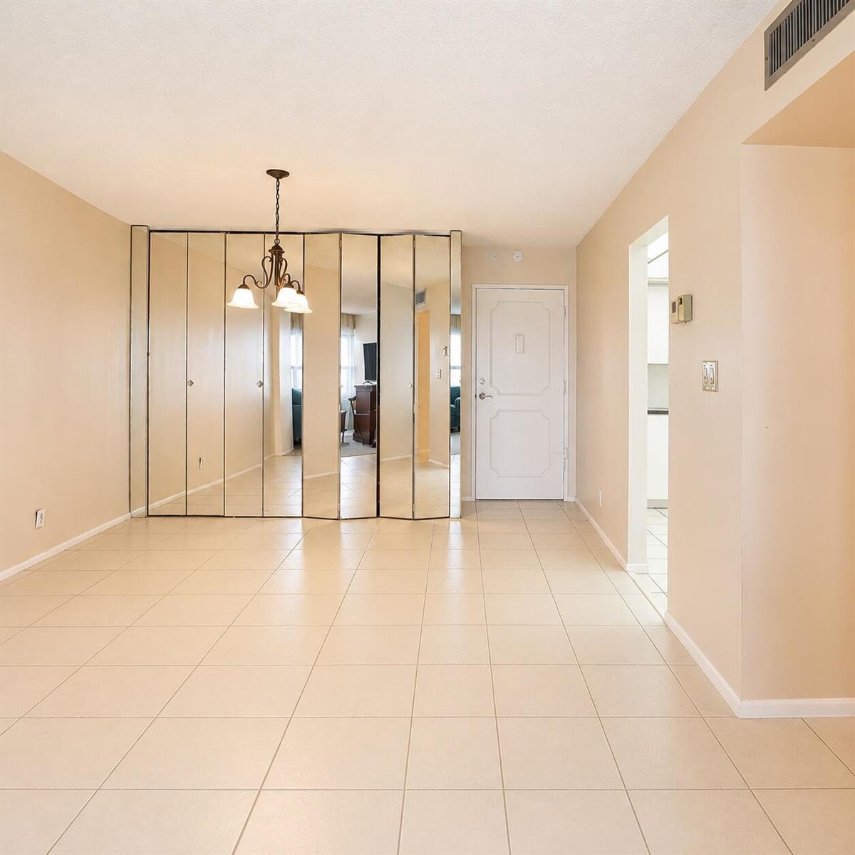 A white kitchen features dark countertops, white cabinetry, a refrigerator, and a vaulted ceiling — 405 N Ocean Boulevard # 1704, Pompano Beach FL 33062, POMPANO BEACH, FL