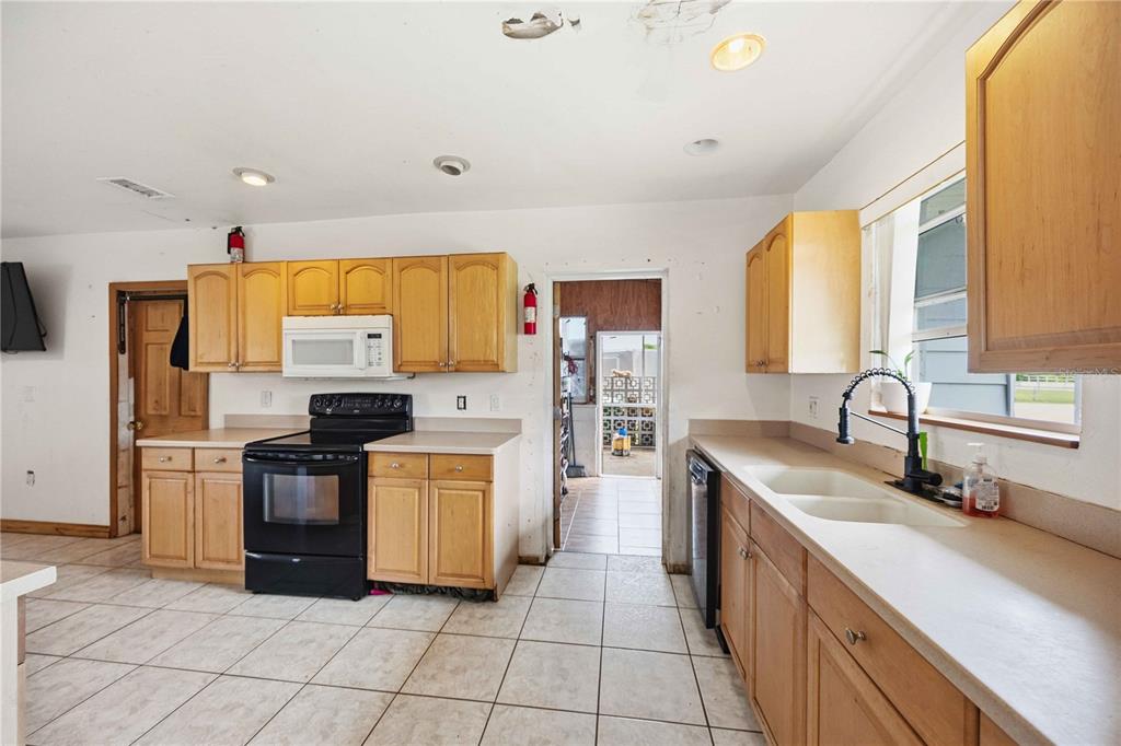 A kitchen with light wood cabinets, black appliances, a double sink, and tiled flooring — 21378 PERCY AVENUE, PORT CHARLOTTE, FL