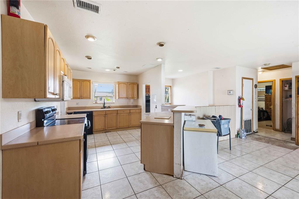 A kitchen with light wood cabinets, tile flooring, and an island with a chest freezer — 21378 PERCY AVENUE, PORT CHARLOTTE, FL