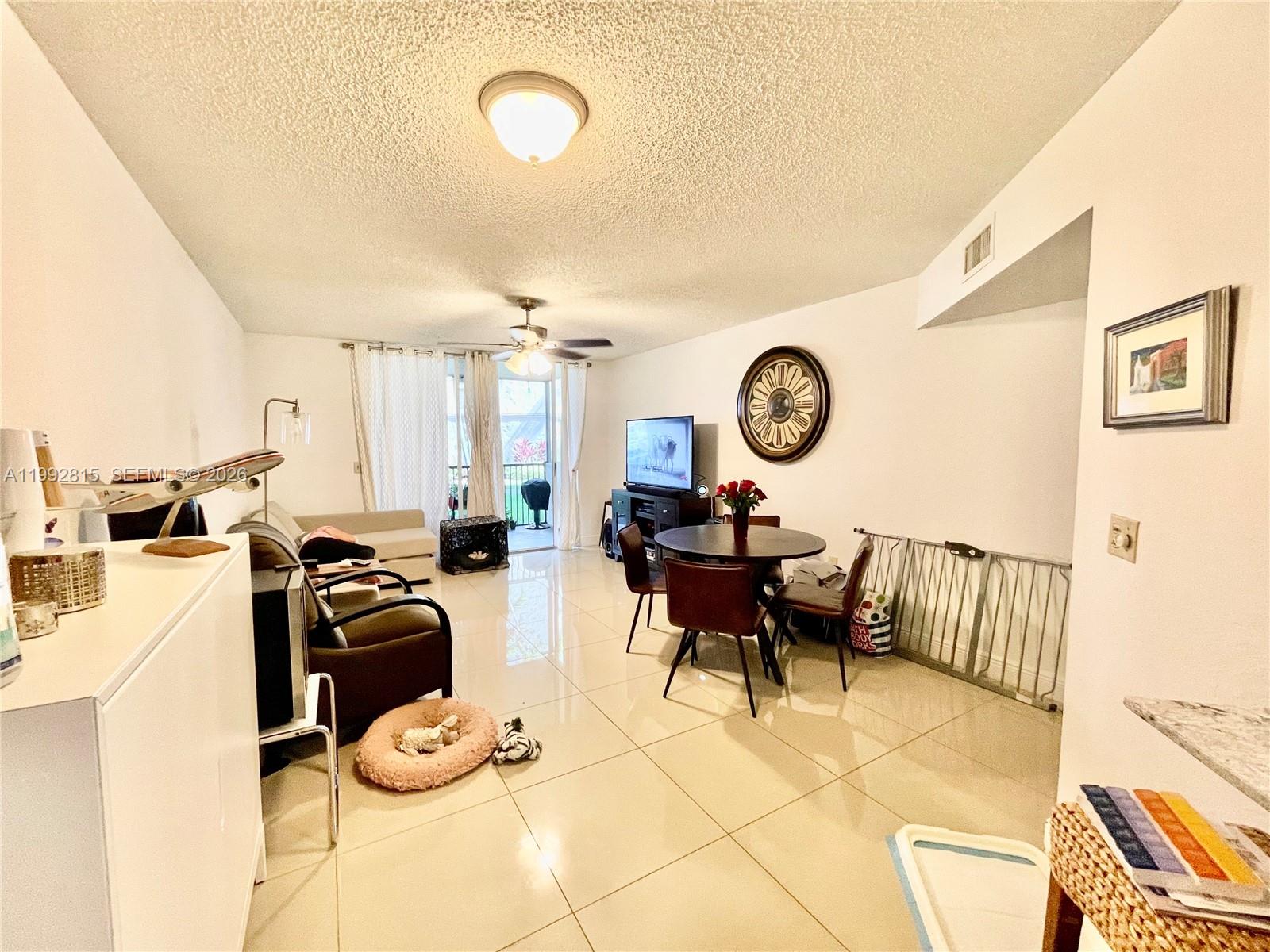 A living and dining area features white tile floors, a ceiling fan, and a balcony — 8255 Lake Dr # 102, Doral FL 33166, DORAL, FL