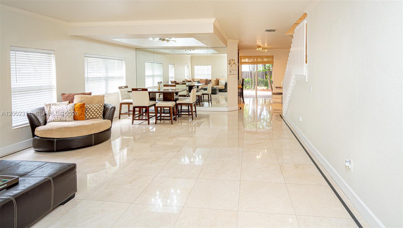 A living and dining area features large light-colored floor tiles and a mirrored wall — 6772 NW 111th Ave, Doral FL 33178, DORAL, FL