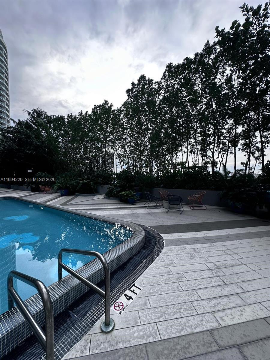 A swimming pool with a metal ladder and a four-foot depth marker on the deck — 121 NE 34th St # 2311, Miami FL 33137, MIAMI, FL