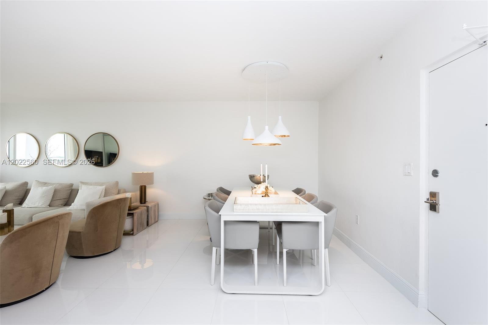A dining area with a white table and grey chairs sits adjacent to a living room — 10275 Collins Ave # 706, Bal Harbour FL 33154, BAL HARBOUR, FL