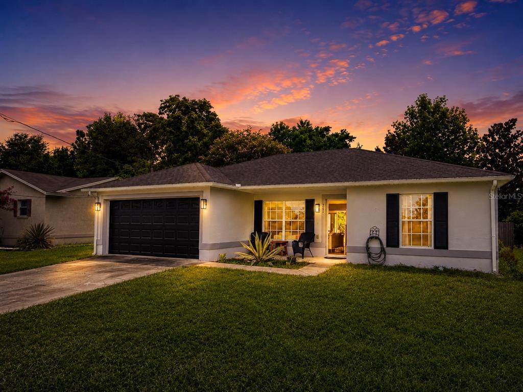 A single-story house with a black garage door and shutters at sunset — 253 WILLIAMS AVENUE, ORANGE CITY, FL