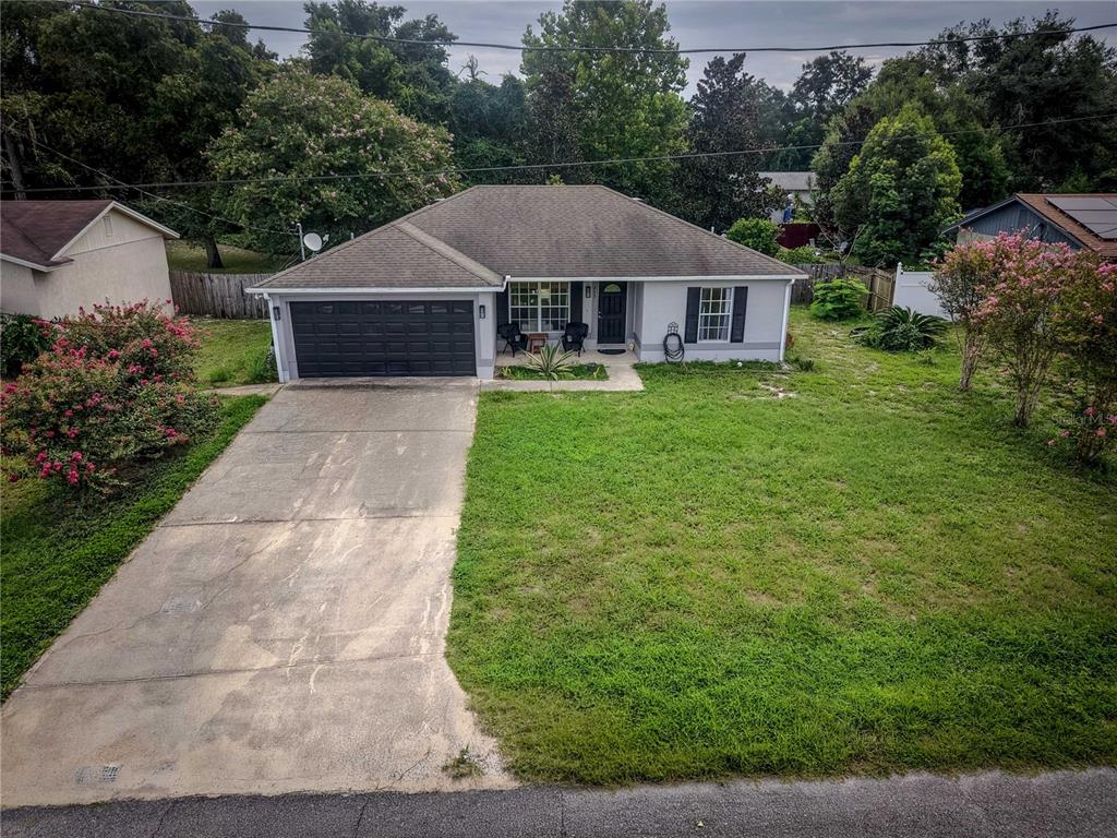 An aerial view of a single-story house with a concrete driveway and a front lawn — 253 WILLIAMS AVENUE, ORANGE CITY, FL