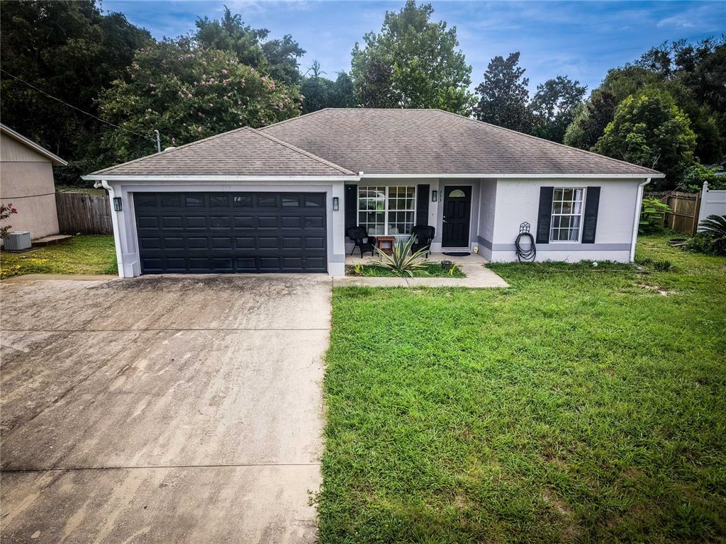 A single-story house with a gray exterior, dark garage door, and a concrete driveway — 253 WILLIAMS AVENUE, ORANGE CITY, FL
