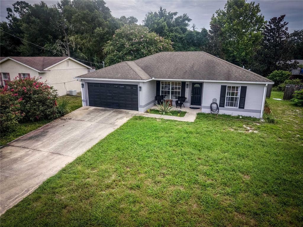 A single-story house with a gray exterior, black garage door, and a concrete driveway — 253 WILLIAMS AVENUE, ORANGE CITY, FL