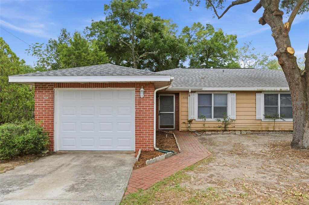 A single-story house with a brick garage, tan siding, and a brick walkway — 8124 OMAHA CIRCLE, SPRING HILL, FL