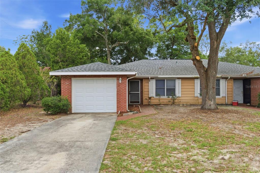 A single-story house with a brick-front garage, tan siding, and a concrete driveway — 8124 OMAHA CIRCLE, SPRING HILL, FL