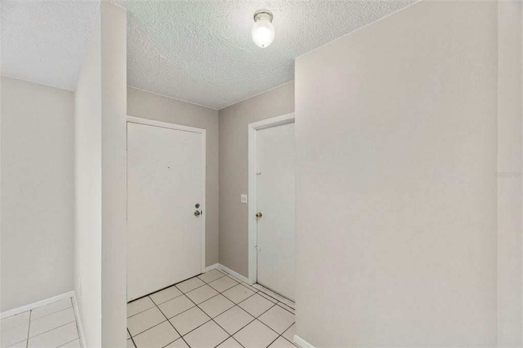 An entryway with white tile flooring, two white doors, and a ceiling light fixture — 8124 OMAHA CIRCLE, SPRING HILL, FL