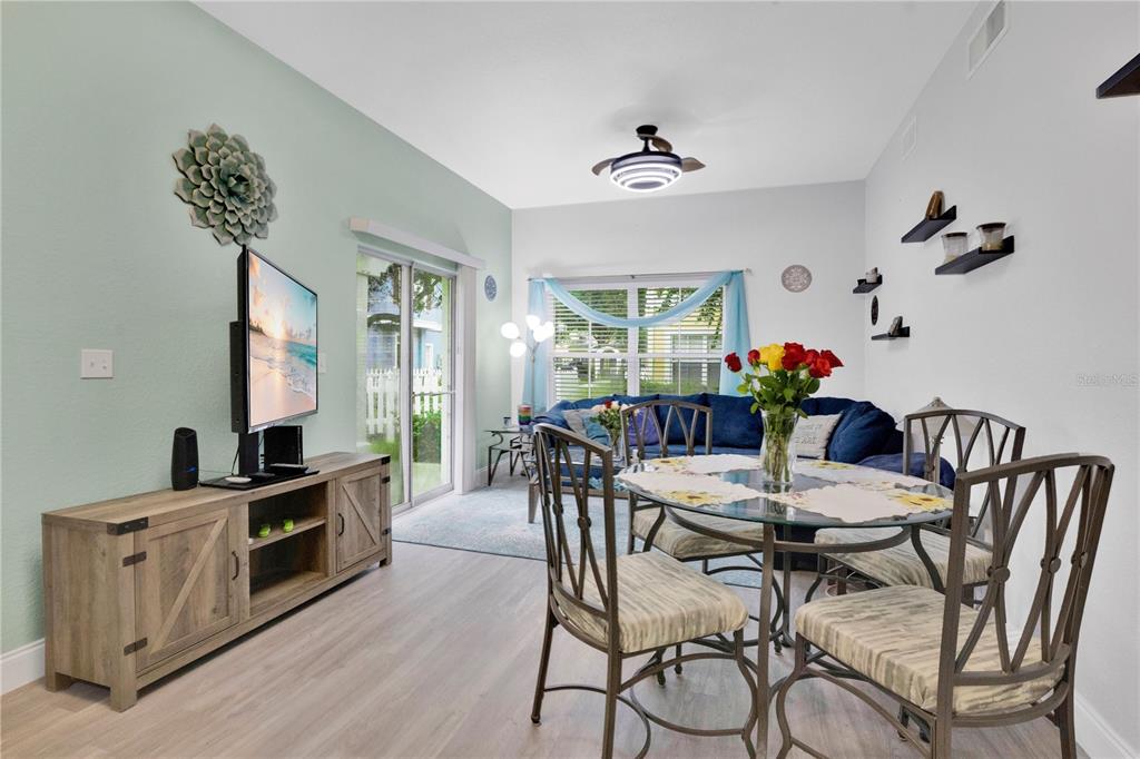 A living and dining area features light wood flooring, a glass-topped table, and a television console — 4005 SAN SEBASTIAN DRIVE UNIT 101, KISSIMMEE, FL