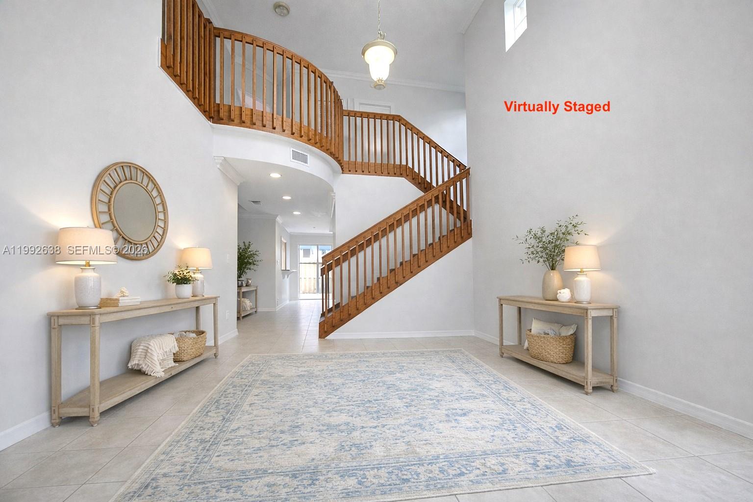 A bright foyer features a curved wooden staircase, tile flooring, and two console tables — 8421 SW 124th Ave # 101, Miami FL 33183, MIAMI, FL