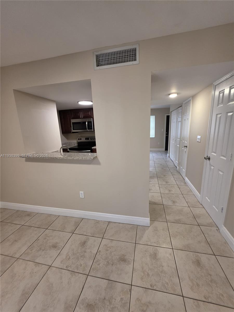 A view from a tiled room looking into a kitchen with a pass-through window — 1990 NW 4th Ct # 7, Miami FL 33136, MIAMI, FL