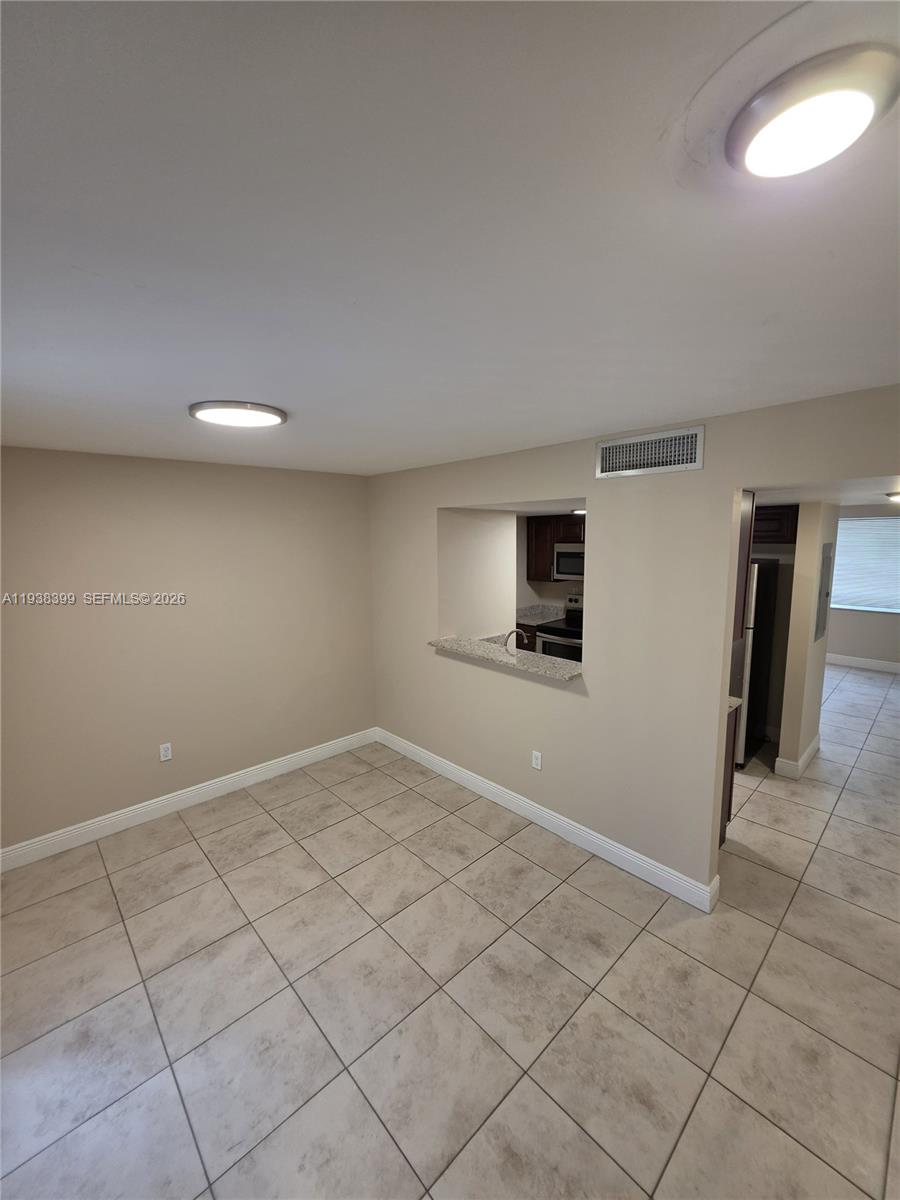 A dining area with tile flooring features a pass-through window looking into the kitchen — 1990 NW 4th Ct # 7, Miami FL 33136, MIAMI, FL
