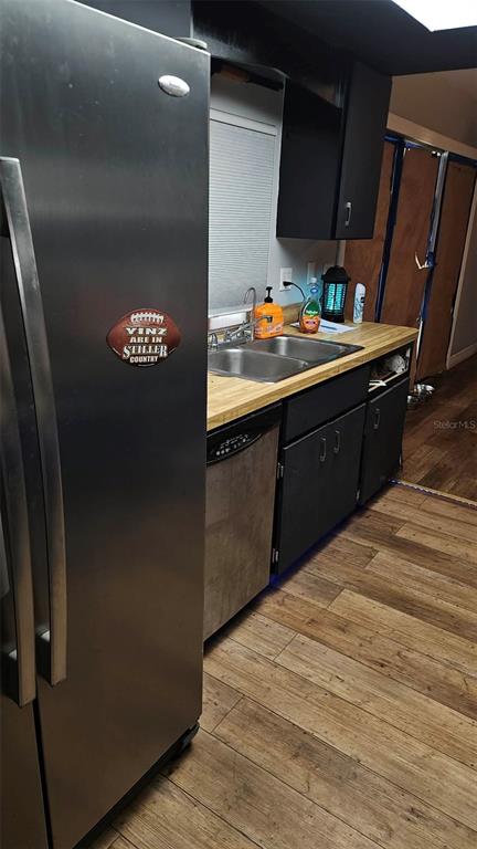 A kitchen features stainless steel appliances, dark cabinets, a wood countertop, and wood-look flooring — 18218 DRIGGERS AVENUE, PORT CHARLOTTE, FL