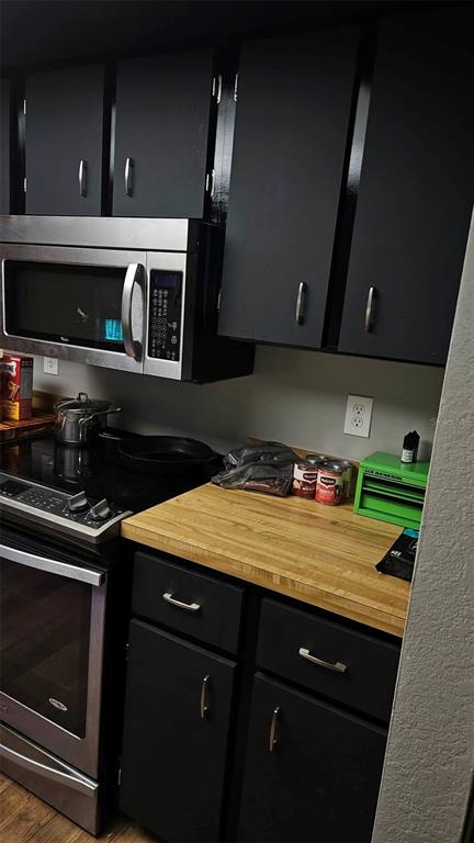 A kitchen features black cabinets, a stainless steel microwave, and a wooden countertop — 18218 DRIGGERS AVENUE, PORT CHARLOTTE, FL
