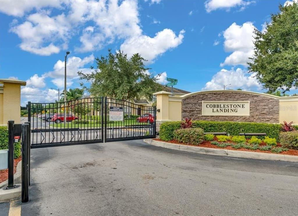 A gated entrance with a stone monument sign reading Cobblestone Landing under a blue sky — 5404 QUARRY ROCK ROAD, LAKELAND, FL
