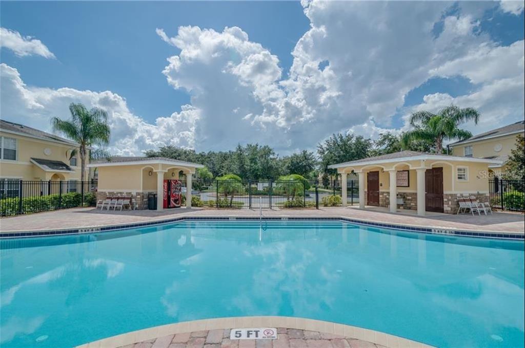A swimming pool sits between two small covered structures with a large cloudy blue sky — 5404 QUARRY ROCK ROAD, LAKELAND, FL