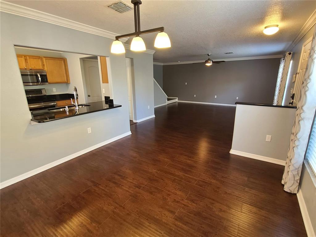 A kitchen with dark countertops overlooks a dining area with dark wood-look flooring — 5404 QUARRY ROCK ROAD, LAKELAND, FL