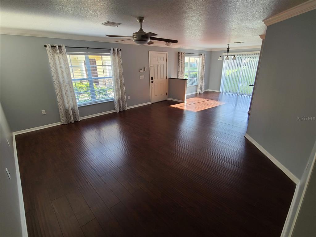 A living room with dark wood flooring, a ceiling fan, and a front door — 5404 QUARRY ROCK ROAD, LAKELAND, FL
