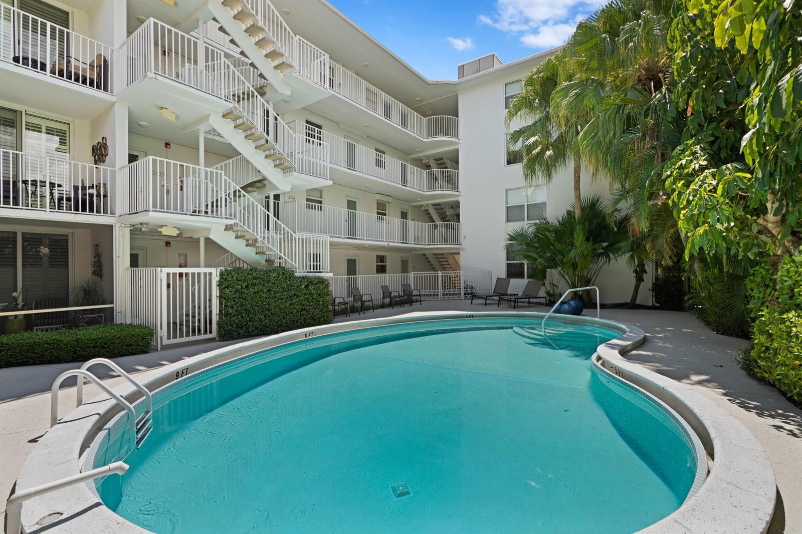 A swimming pool sits in the courtyard of a multi-story apartment building with exterior staircases — 401 Peruvian Avenue # 3020, Palm Beach FL 33480, PALM BEACH, FL