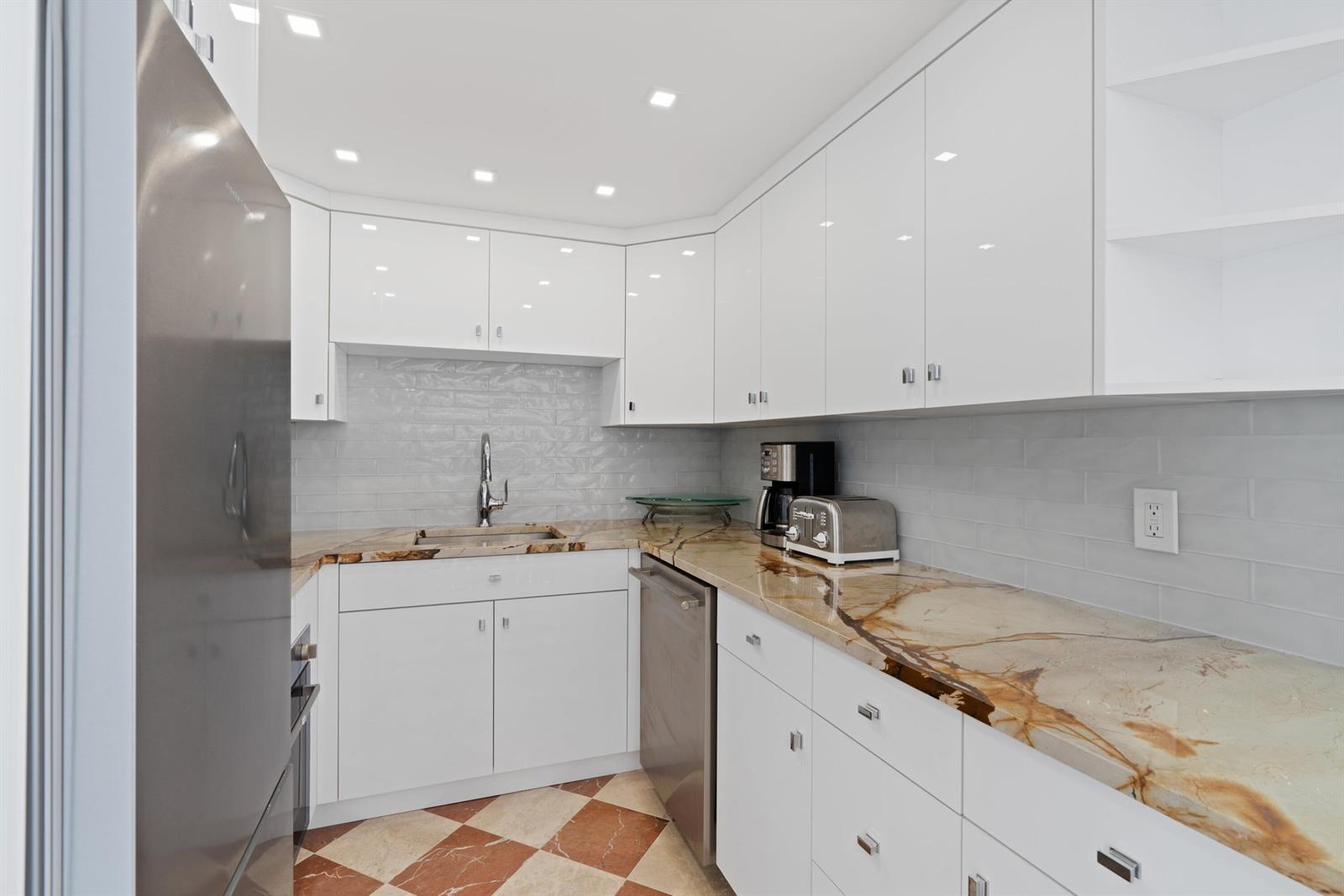 A kitchen features white cabinets, marble countertops, a stainless steel dishwasher, and checkered tile flooring — 401 Peruvian Avenue # 3020, Palm Beach FL 33480, PALM BEACH, FL