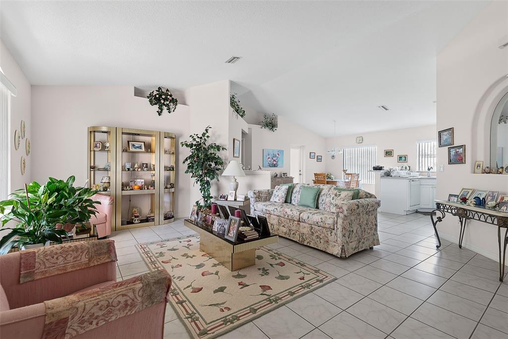 A living room with tile floors, a floral sofa, a glass display cabinet, and area rug — 52 FENWICK LANE, PALM COAST, FL