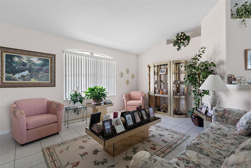 A living room features tiled floors, a floral sofa, pink armchairs, and a mirrored coffee table — 52 FENWICK LANE, PALM COAST, FL