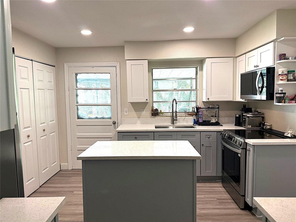 A kitchen features gray lower cabinets, white upper cabinets, a central island, and stainless appliances — 39246 LIZABETH CIRCLE, ZEPHYRHILLS, FL