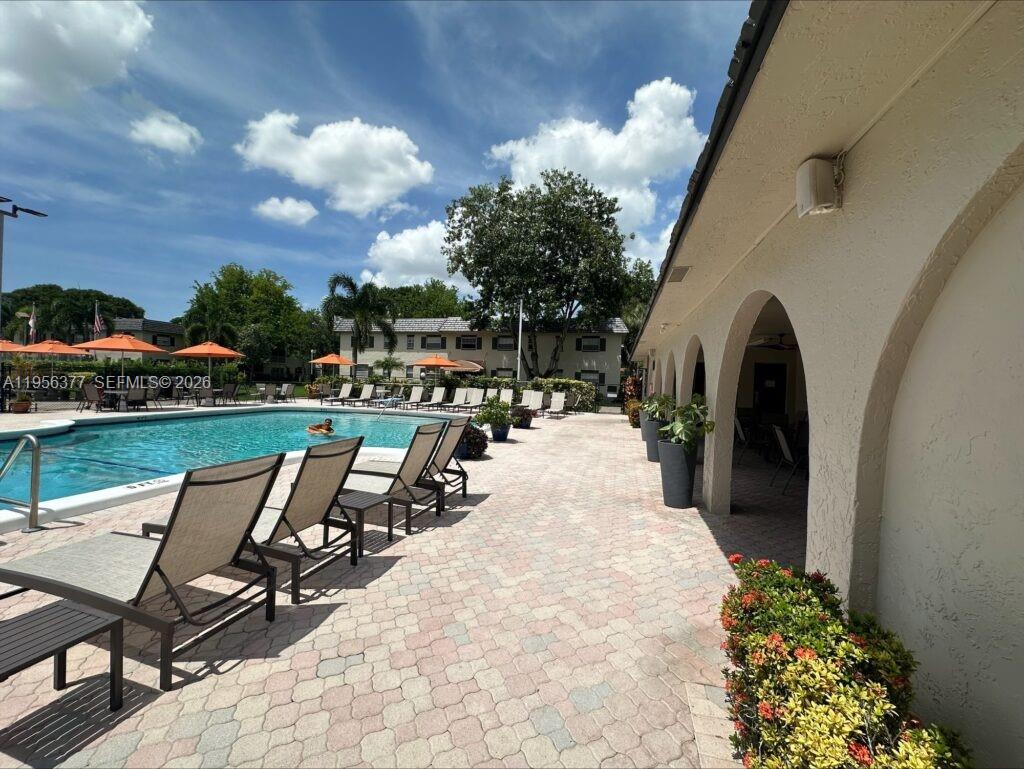 A swimming pool area features lounge chairs on a paved deck beside a covered patio — 5661 SW 2nd Ct # 101, Margate FL 33068, MARGATE, FL