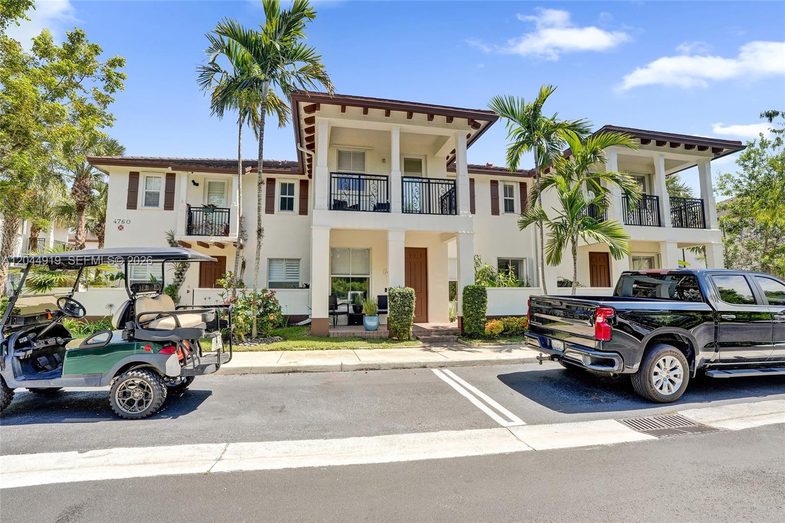 A two-story residential building with balconies, palm trees, a golf cart, and a pickup truck — 4760 Mimosa Pl # 1015, Coconut Creek FL 33073, COCONUT CREEK, FL