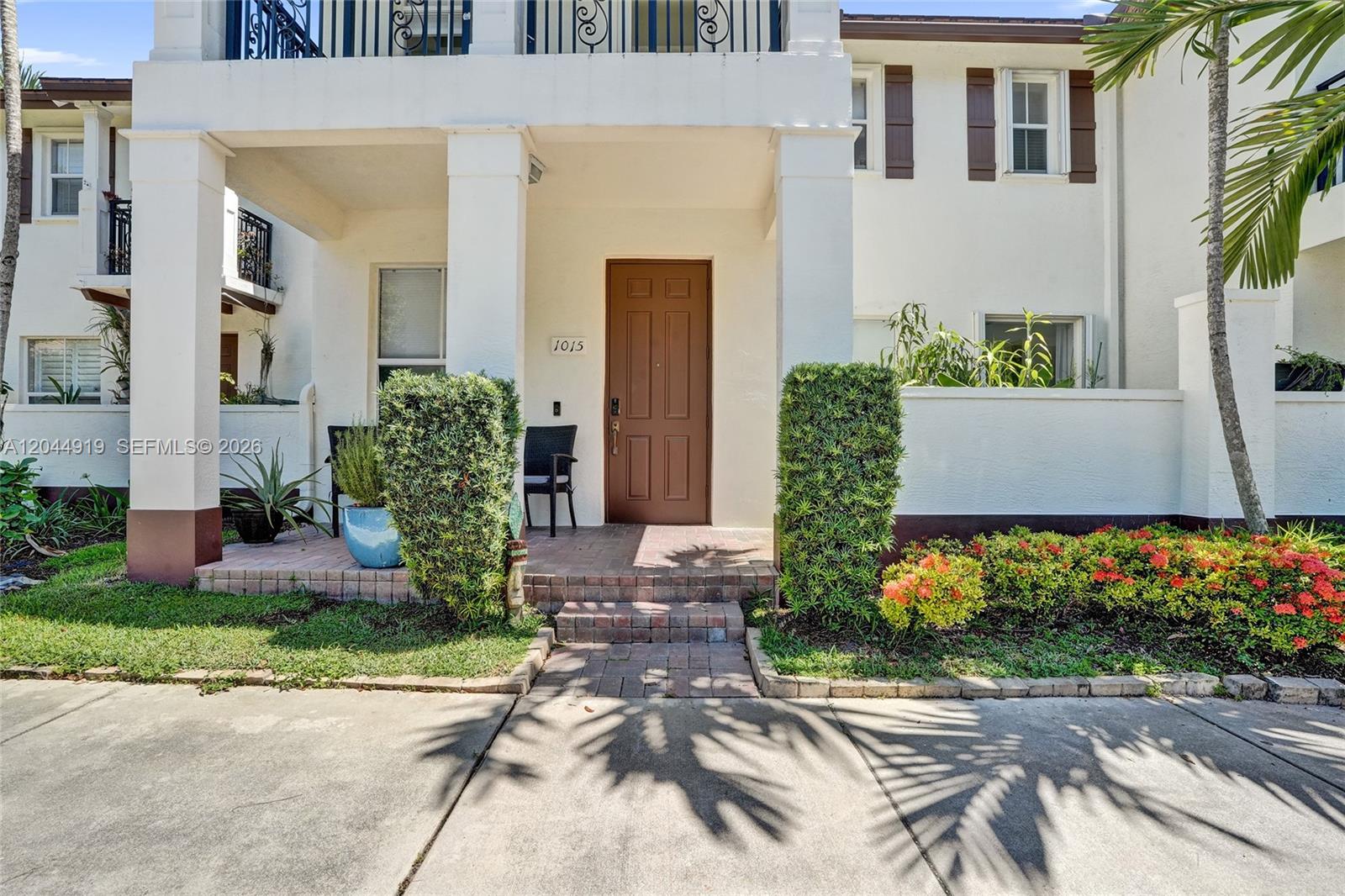 A brown front door is centered on the porch of a white two-story townhouse — 4760 Mimosa Pl # 1015, Coconut Creek FL 33073, COCONUT CREEK, FL