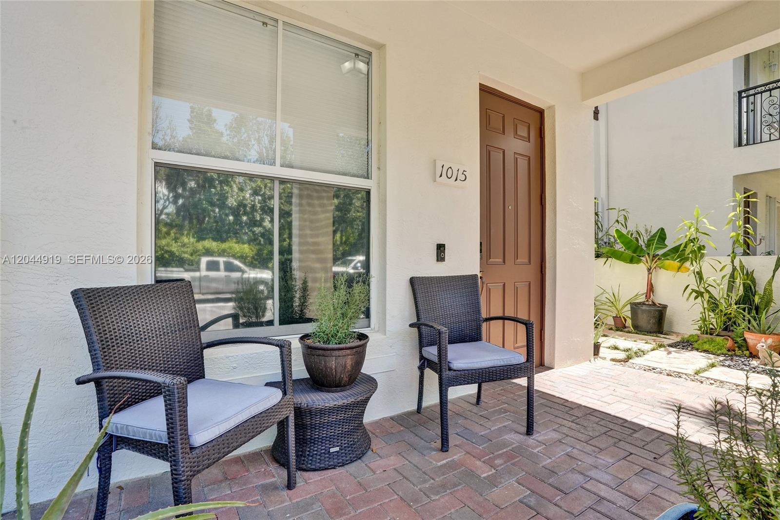 A paved patio features two wicker chairs, a small side table, and potted plants — 4760 Mimosa Pl # 1015, Coconut Creek FL 33073, COCONUT CREEK, FL