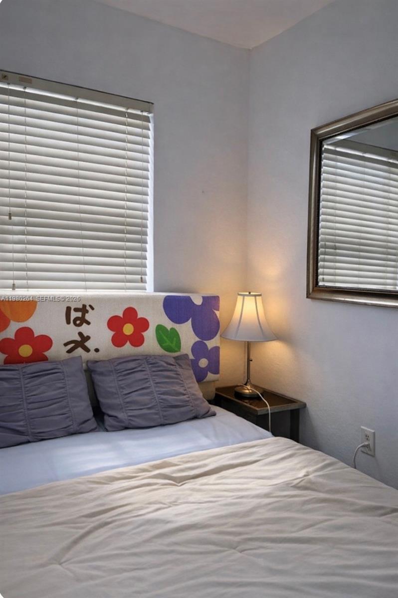 A bedroom features a bed with a floral headboard, a bedside lamp, and a wall mirror — 3301 Spanish Moss Ter # 512, Lauderhill FL 33319, LAUDERHILL, FL