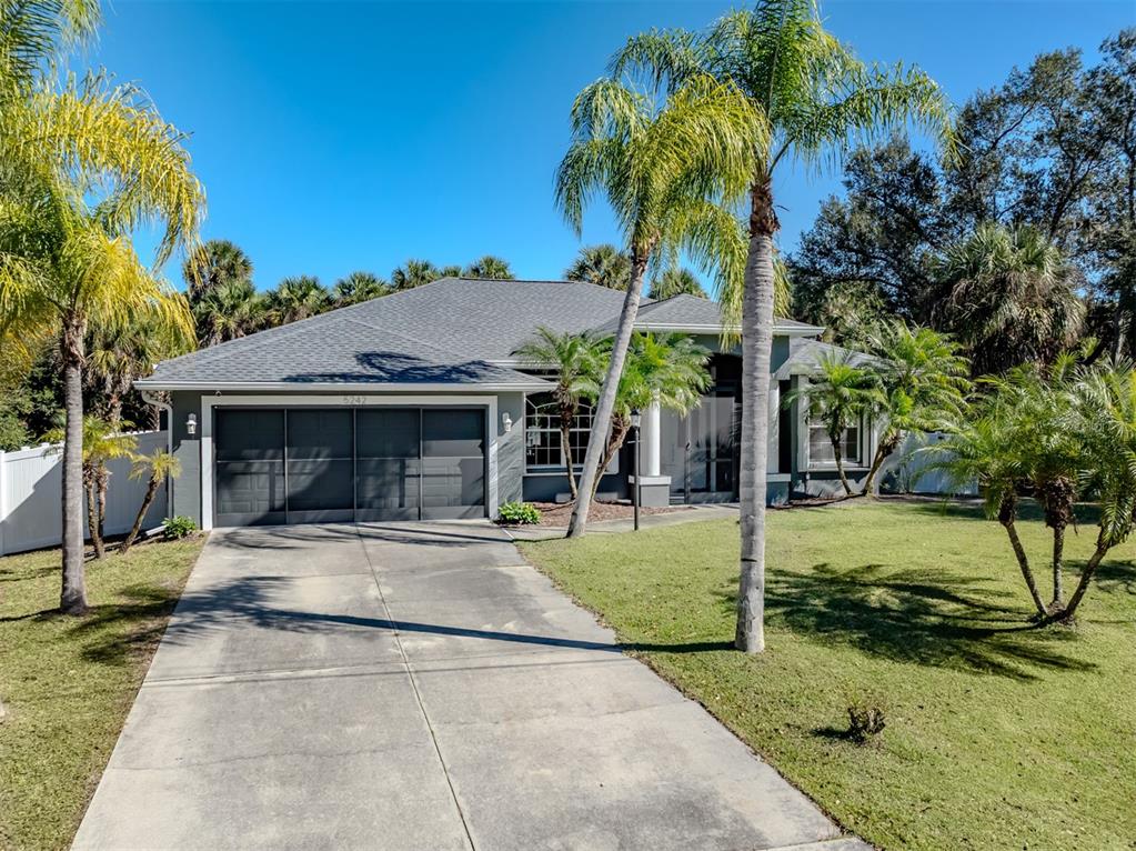 A single-story house with a gray garage, a concrete driveway, and palm trees in front — 5242 ABDELLA LANE, NORTH PORT, FL