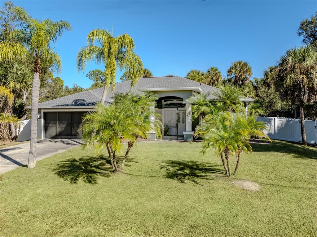 A single-story house with a gray roof, two-car garage, and palm trees in the front yard — 5242 ABDELLA LANE, NORTH PORT, FL