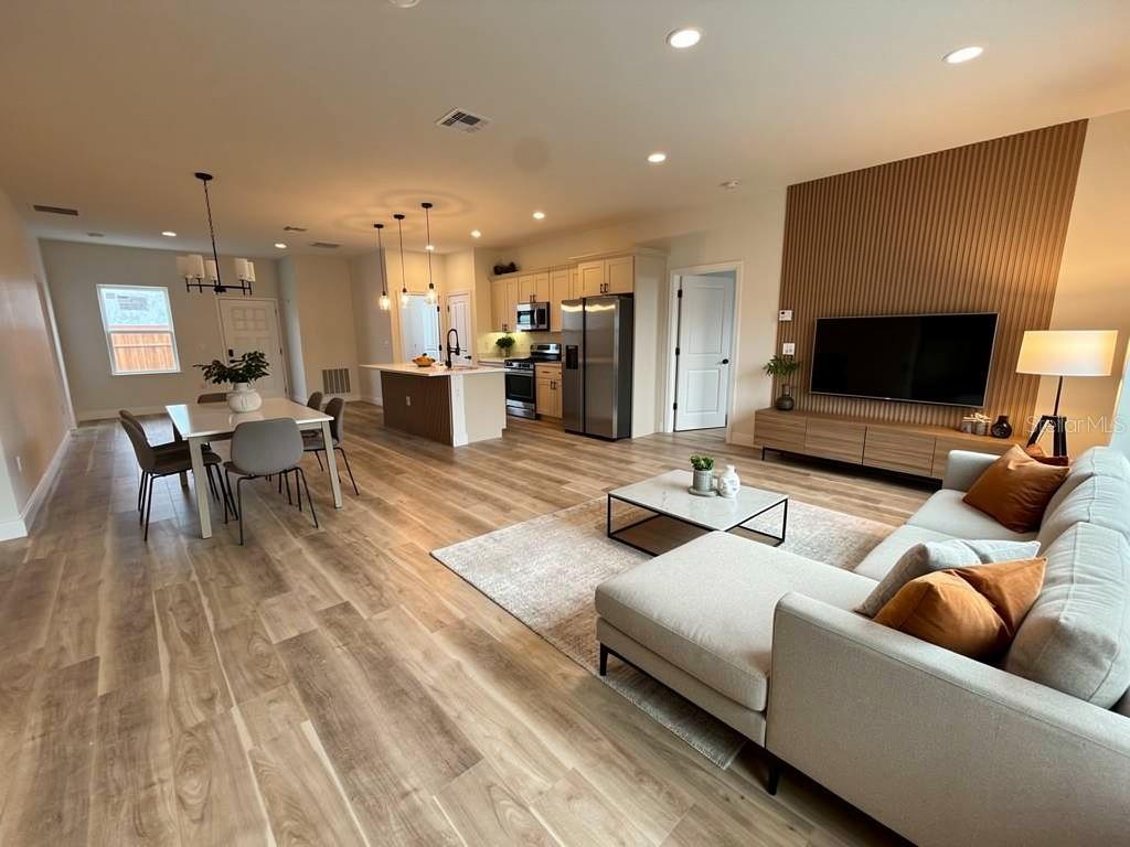 An open-concept living room and kitchen feature wood-look flooring and a slatted wood accent wall — 23419 GEMSTONE AVENUE, PORT CHARLOTTE, FL
