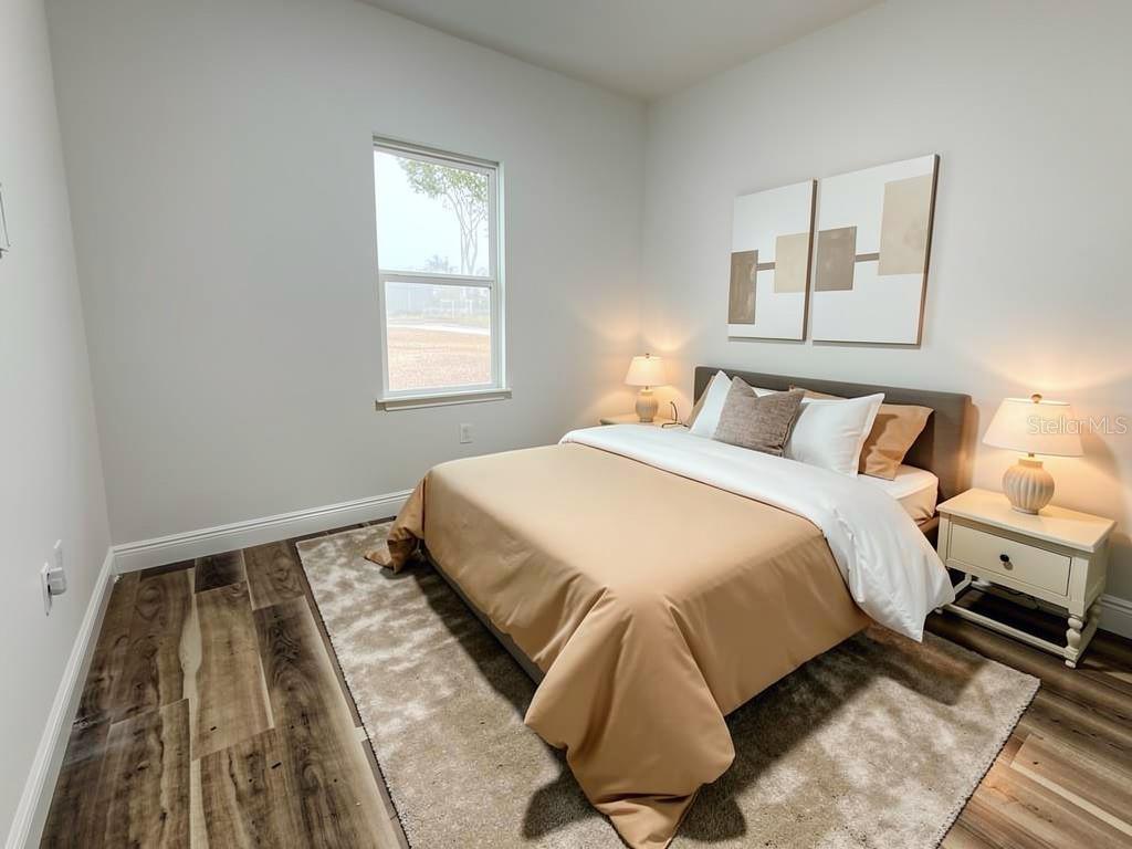 A bedroom features a bed with tan bedding, a rug, and two bedside lamps — 23419 GEMSTONE AVENUE, PORT CHARLOTTE, FL