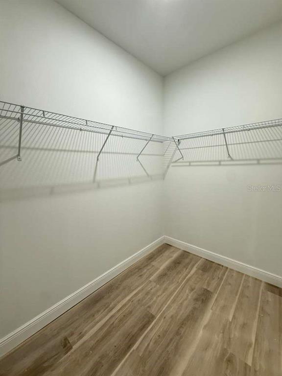 A walk-in closet features white walls, wood-look flooring, and white wire shelving — 23419 GEMSTONE AVENUE, PORT CHARLOTTE, FL