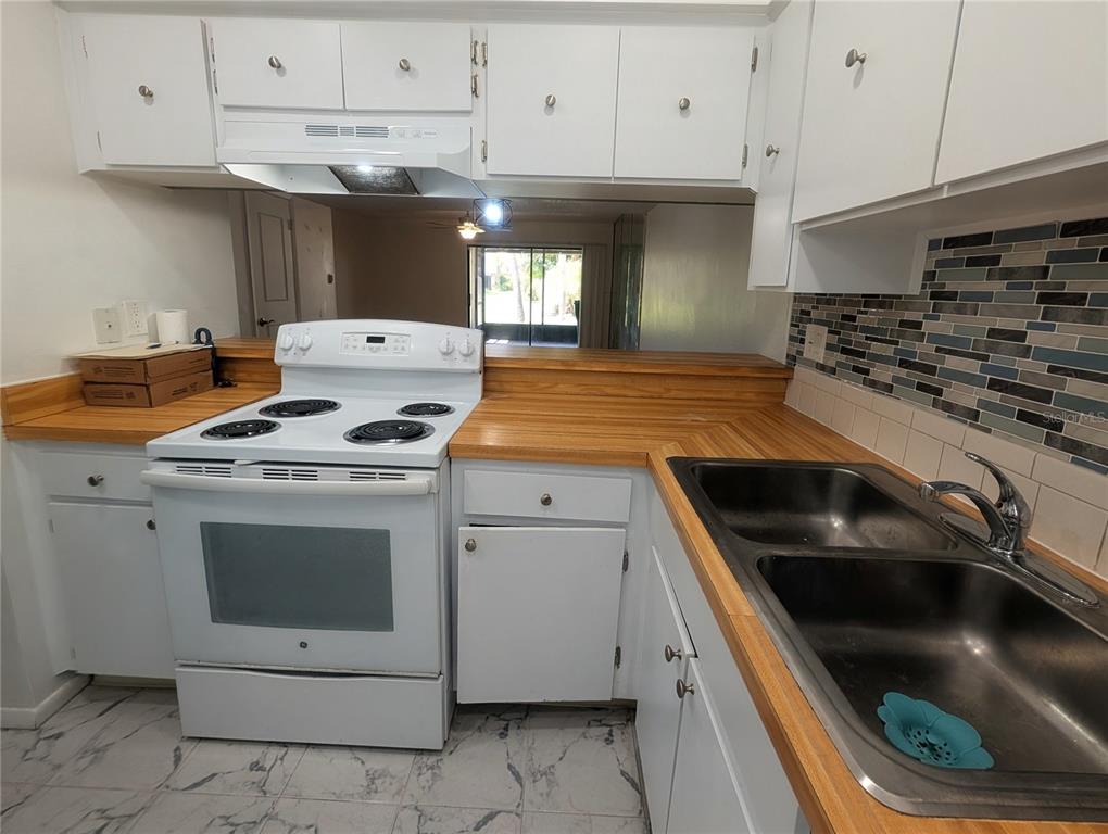 A dining area with wood-look flooring, a modern pendant light, and a kitchen pass-through window — 9209 SEMINOLE BOULEVARD UNIT 67, SEMINOLE, FL