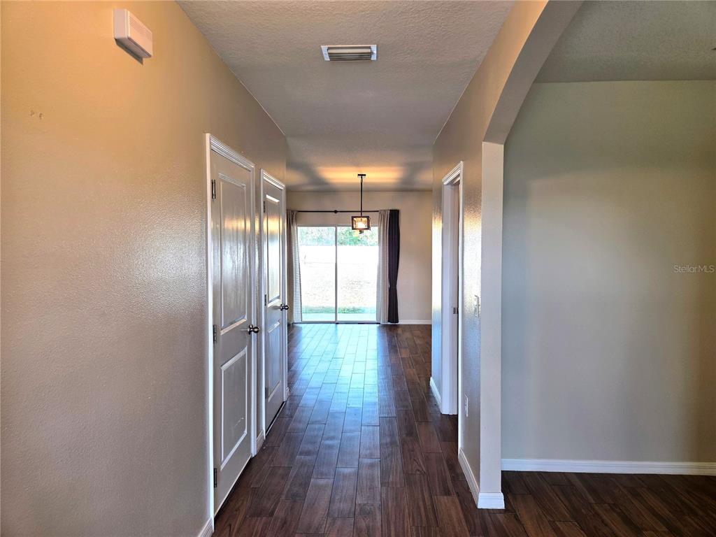A hallway with wood-look tile flooring leads to a dining area with sliding glass doors — 109 TIERRA VERDE WAY, BRADENTON, FL