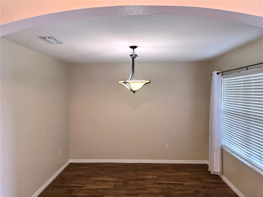 A dining room with wood-look flooring, a central pendant light, and a window with blinds — 109 TIERRA VERDE WAY, BRADENTON, FL