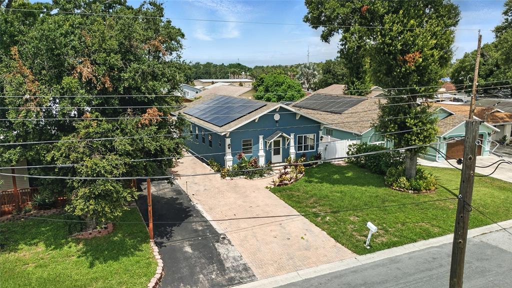 A blue bungalow with a white front door, brick walkway, and tropical landscaping — 7012 N HUBERT AVENUE, TAMPA, FL