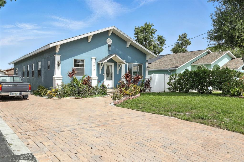 An elevated view of a blue house with solar panels and a paved driveway — 7012 N HUBERT AVENUE, TAMPA, FL