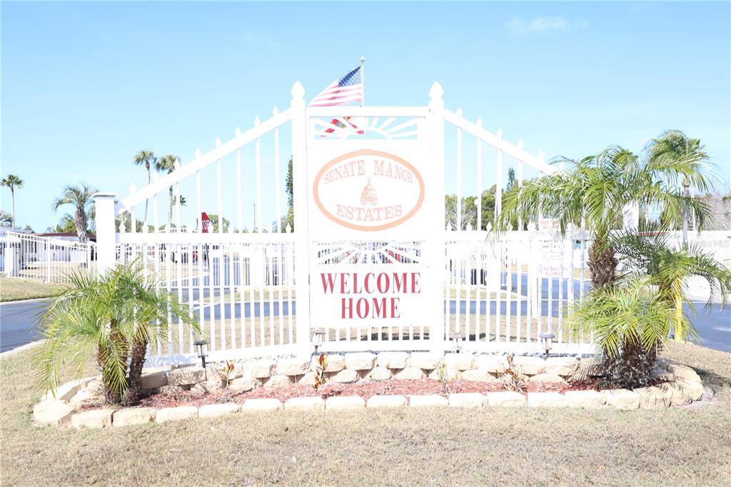 A white metal gate with a Senate Manor Estates sign stands at a community entrance — 6608 ROOSEVELT DRIVE, PORT RICHEY, FL