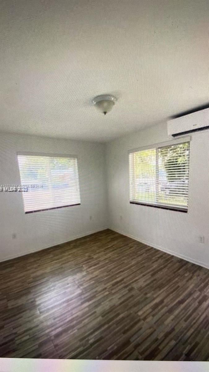 An empty room features wood-look flooring, white walls, two windows with blinds, and a mini-split — 7637 NW 3rd Ave, Miami FL 33150, MIAMI, FL