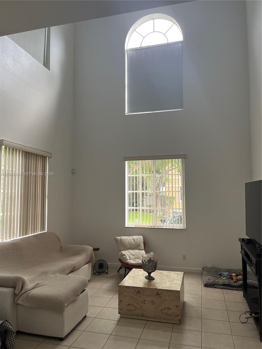 A living room features high ceilings, a large arched window, and light-colored tile flooring — 5347 SW 40th Ave # 5347, Dania Beach FL 33314, DANIA BEACH, FL