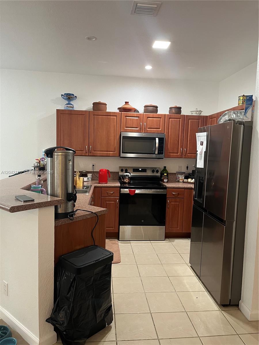 A kitchen features wood cabinets, stainless steel appliances, and a peninsula counter with a trash can — 5347 SW 40th Ave # 5347, Dania Beach FL 33314, DANIA BEACH, FL