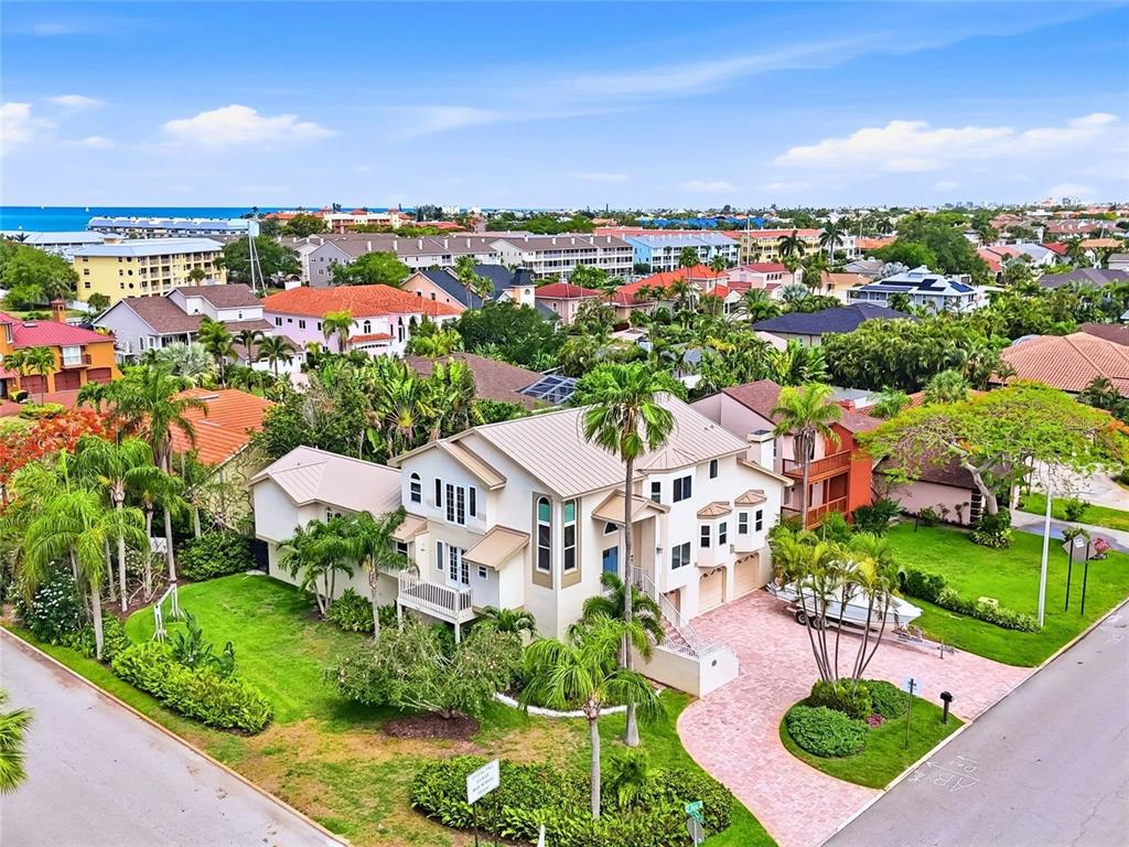 An aerial view shows a multi-story house with a metal roof and a paved driveway — 1156 2ND AVENUE S, TIERRA VERDE, FL