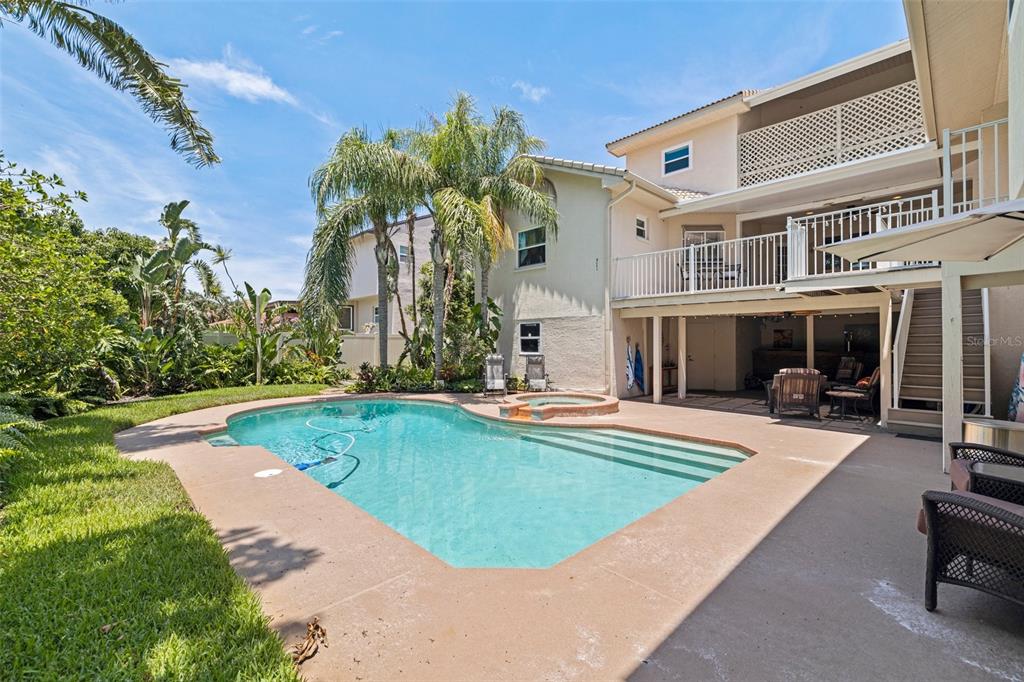 A backyard features a swimming pool with a spa, a patio, and a two-story house — 1156 2ND AVENUE S, TIERRA VERDE, FL